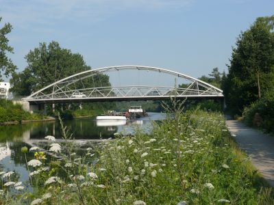 A picturesque scene: the canal with flowers and a calmly sailing vessel.